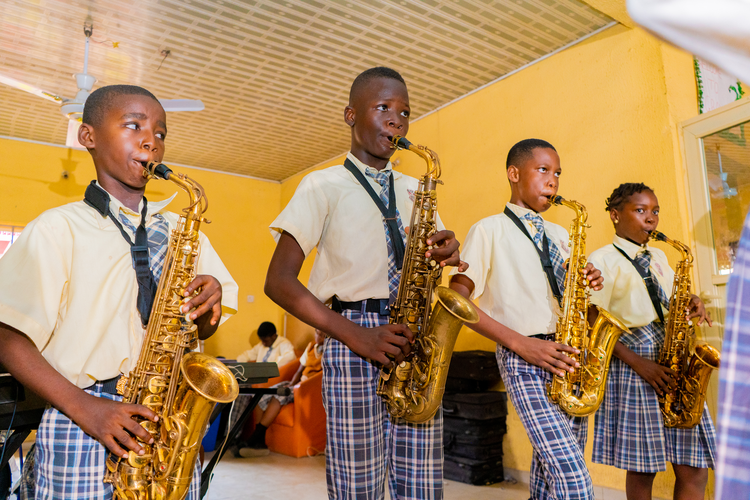 Four college students playing the saxophone during music class