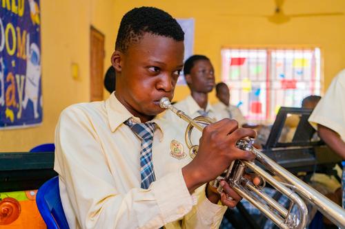 A male college student blowing the trumpet during music class