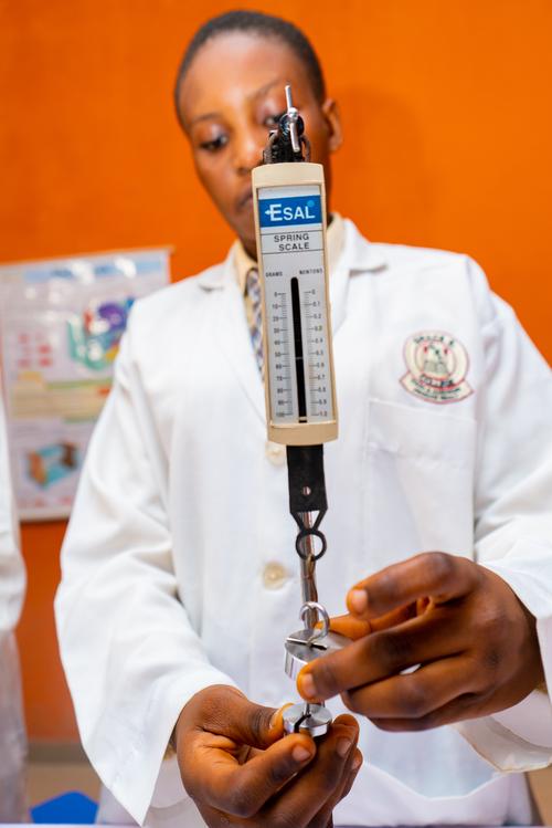 A female college student using a spring scale in the physics laboratory