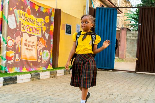 A female primary student walking into the school