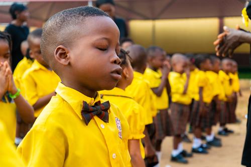 A male primary student with eyes closed during the assembly