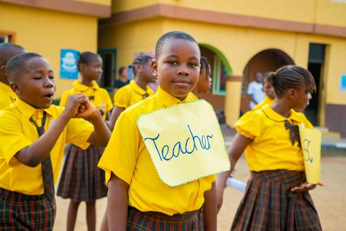 A male primary student with a teacher tag during a presentation on the assembly ground