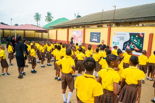 A primary teacher addressing pupils on the assembly ground