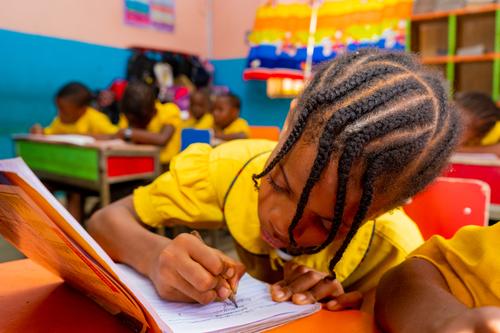 A female primary pupil writing in a classroom